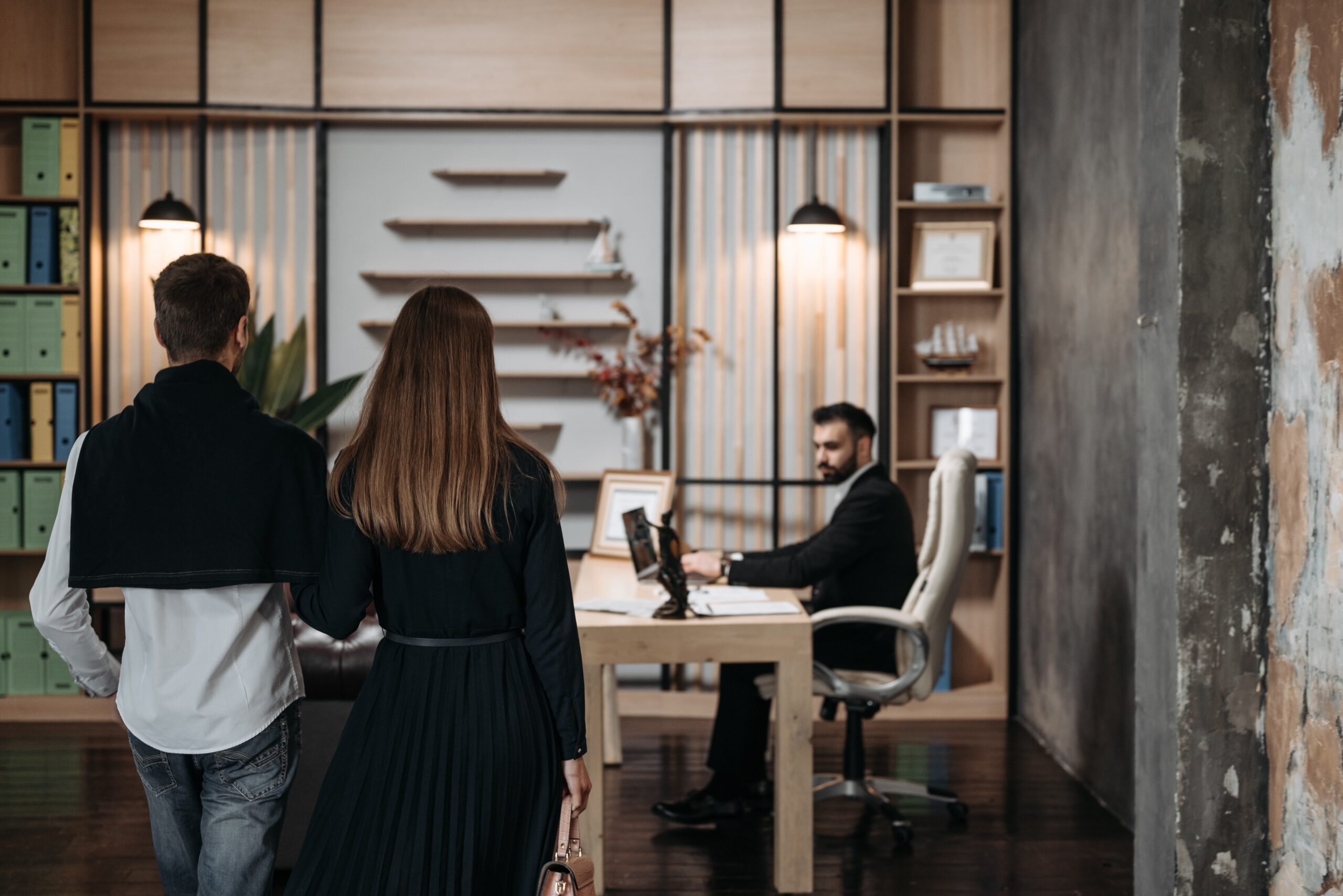 A couple walking into a meeting with a man waiting