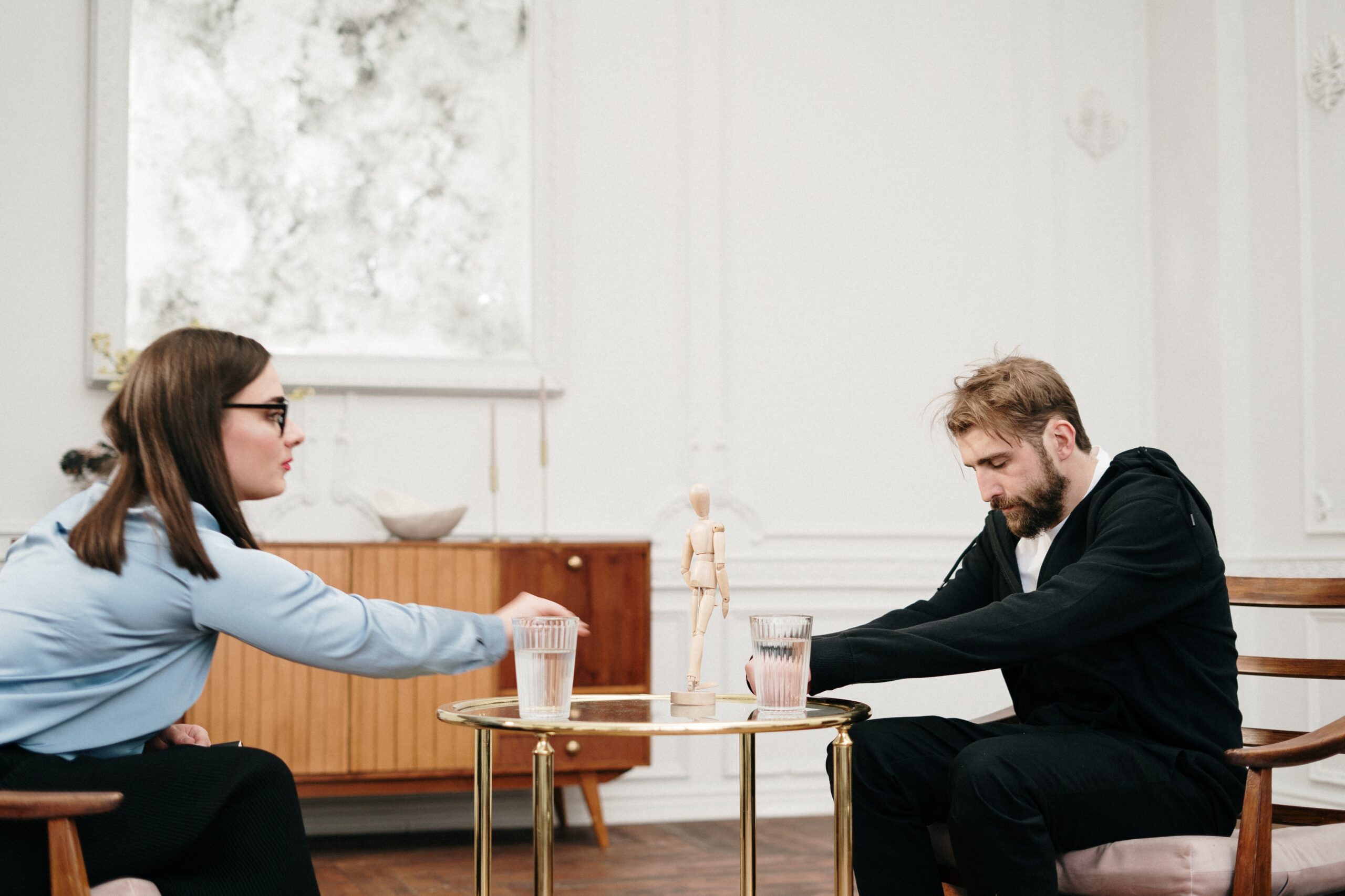 A man looking sad sitting across a woman