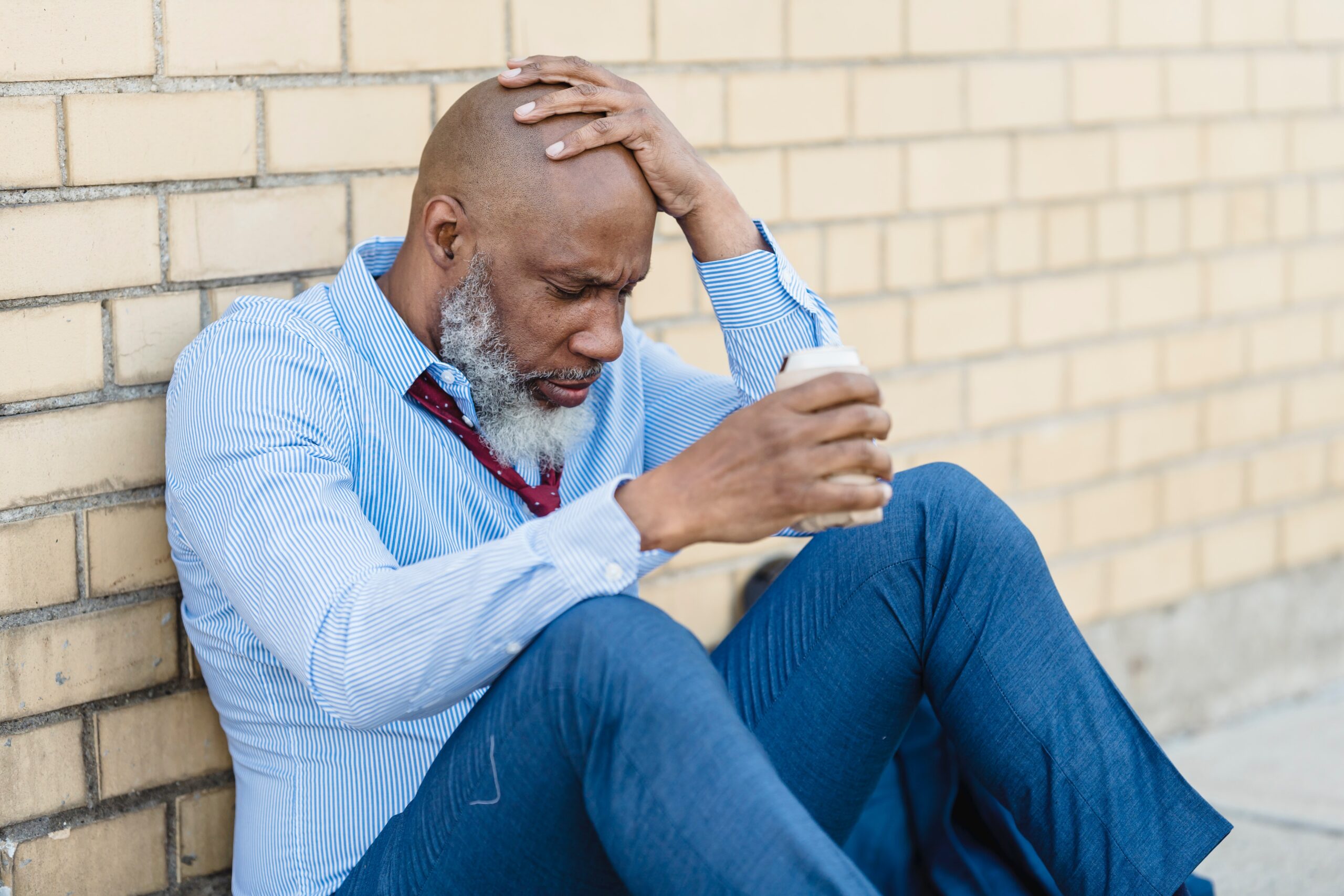 A man sitting on the floor while drinking