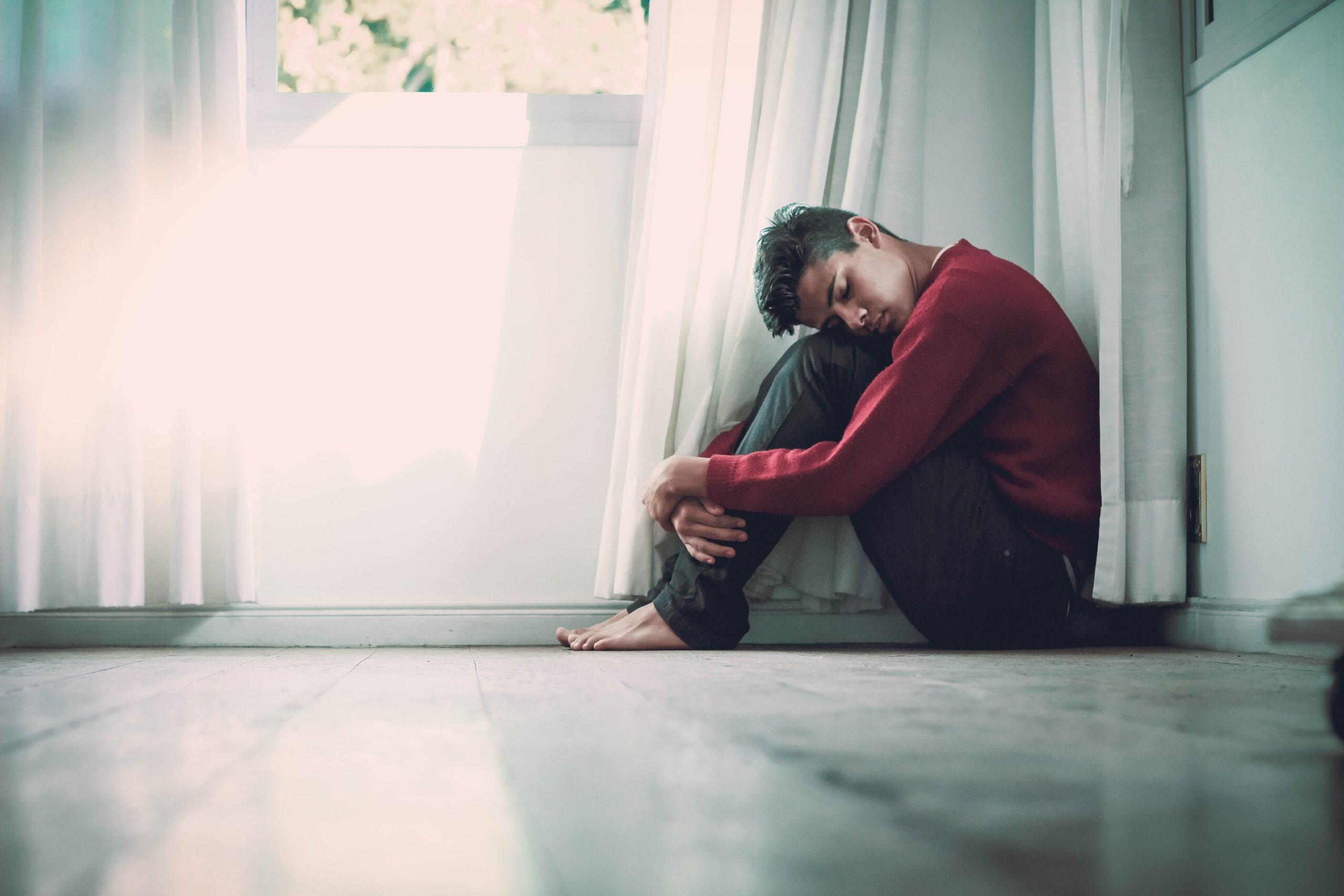 a man sitting on the floor in front of a window