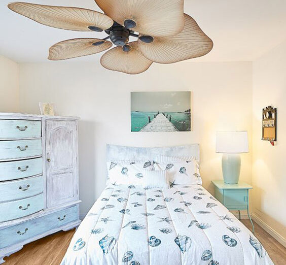 a bedroom with a bed, dresser and ceiling fan