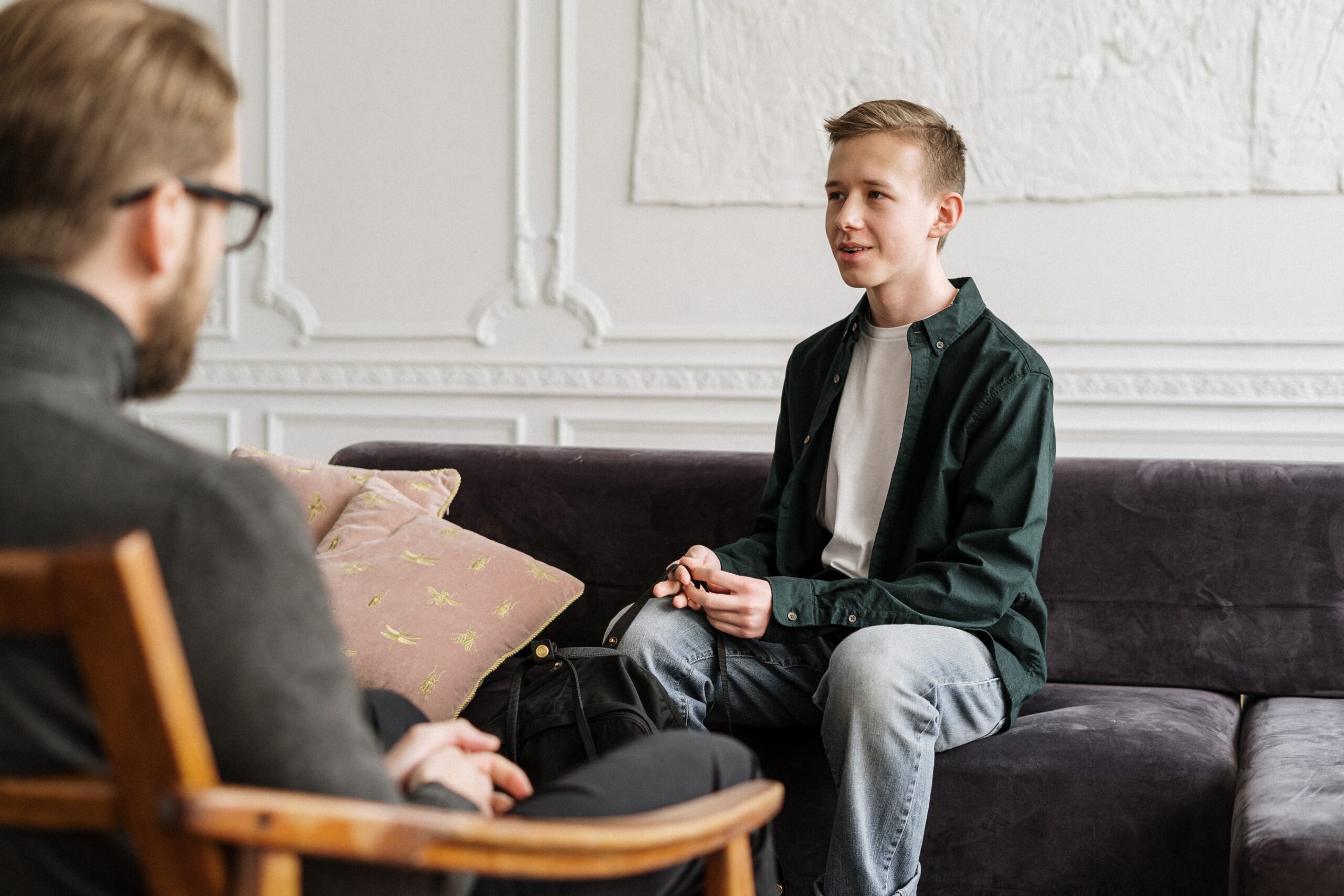 a man sitting on a couch talking to another man